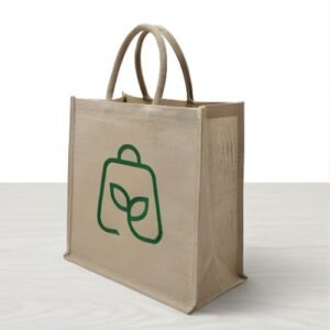 A tan jute tote bag with a green leaf- shaped logo printed on the front, standing on a light-colored surface against a plain background.