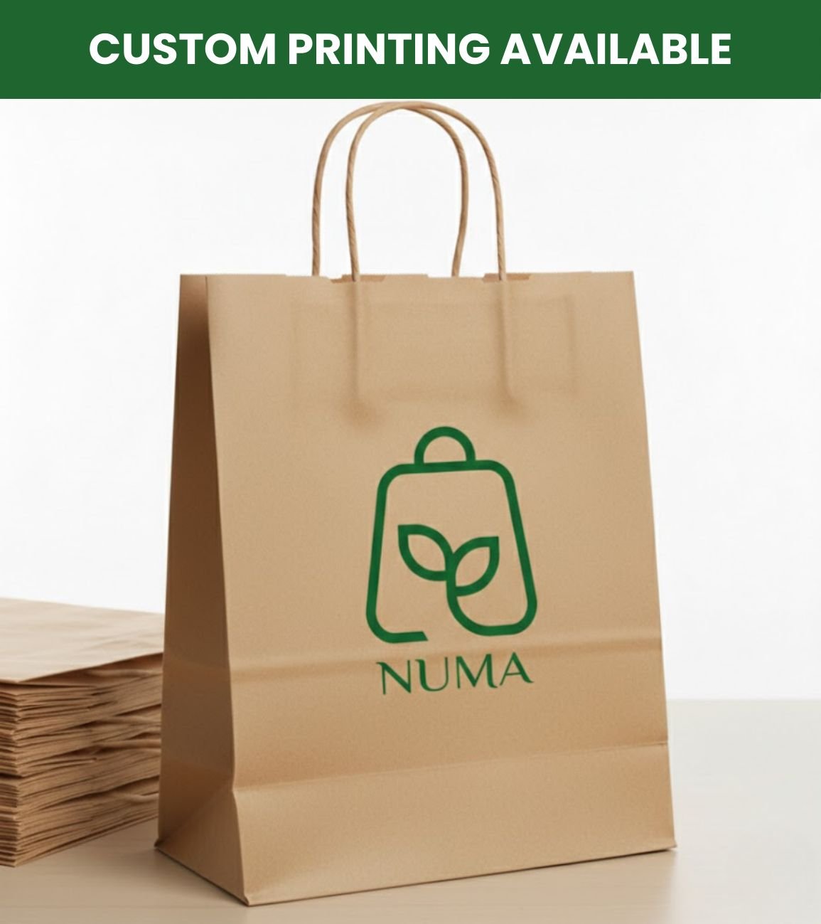 A brown kraft paper shopping bag stands on a
table next to a stack of folded paper bags. The
bag features twisted paper handles and has
the green Numa brand logo printed on the
front, with text above that reads CUSTOM
PRINTING AVAILABLE
.